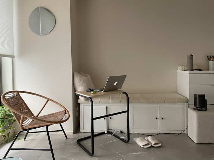 Beige-toned small room home office featuring a rattan chair, storage bench, and compact desk with a modern natural feel