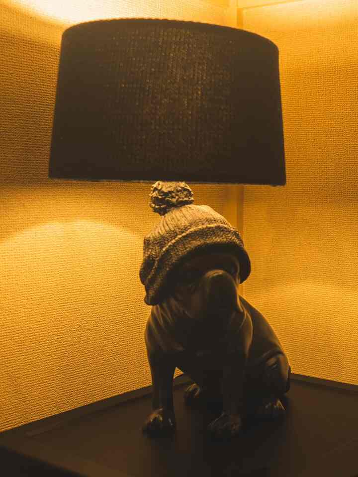 温かみのある黄色い光が背景を包み、黒い犬の形をしたテーブルランプが置かれた雰囲気のある空間