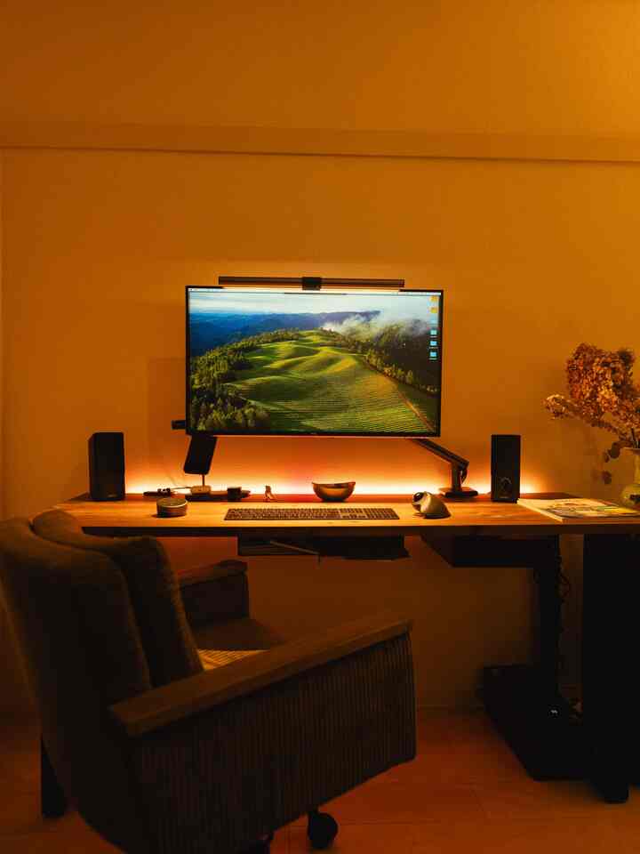 Warm wood-tone compact home office featuring monitor and speakers arranged for remote work