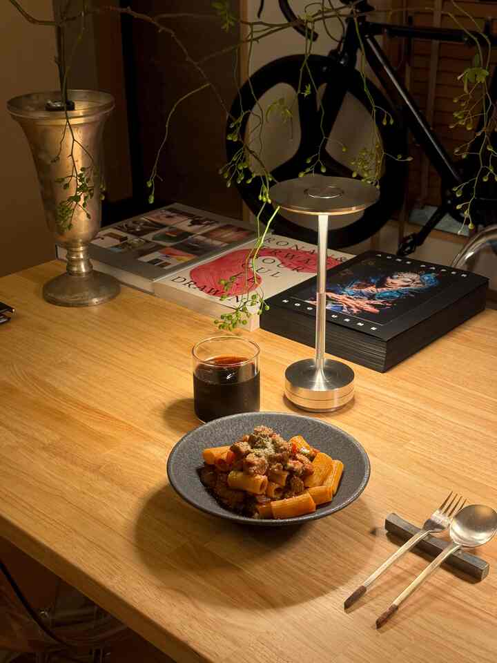 ナチュラルカラーのダイニングルーム、木製のダイニングテーブルにテーブルランプとカトラリーが配置された温かみのあるインテリア