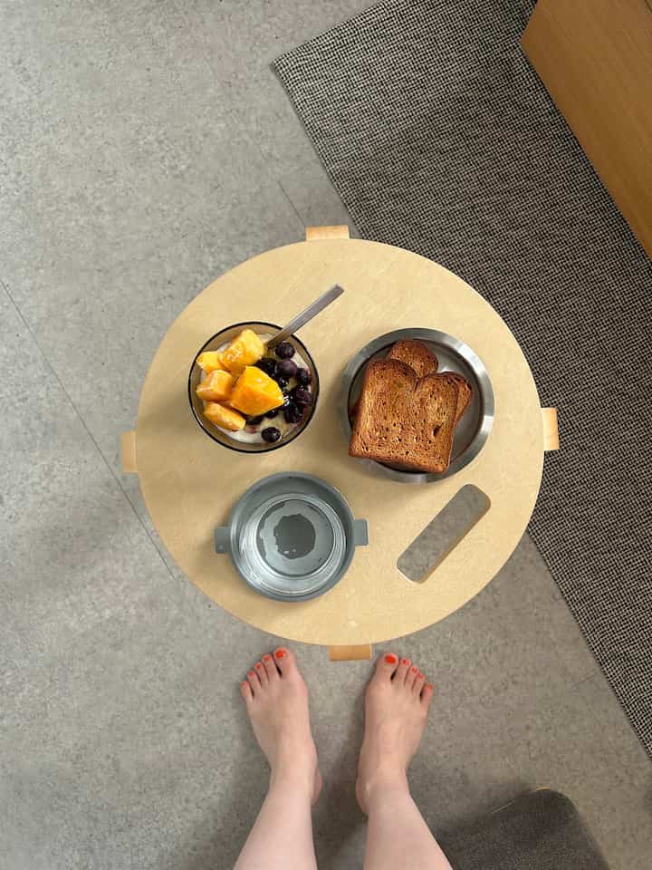 Beige round tray on gray floor in a compact studio apartment breakfast setting