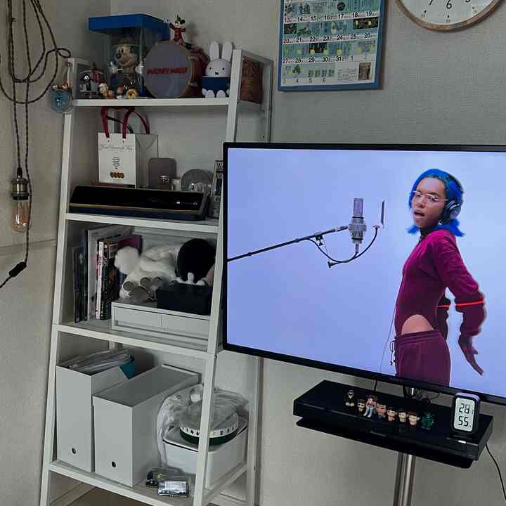 White-toned living space for a single household featuring a shelf and TV stand with a clean, compact atmosphere