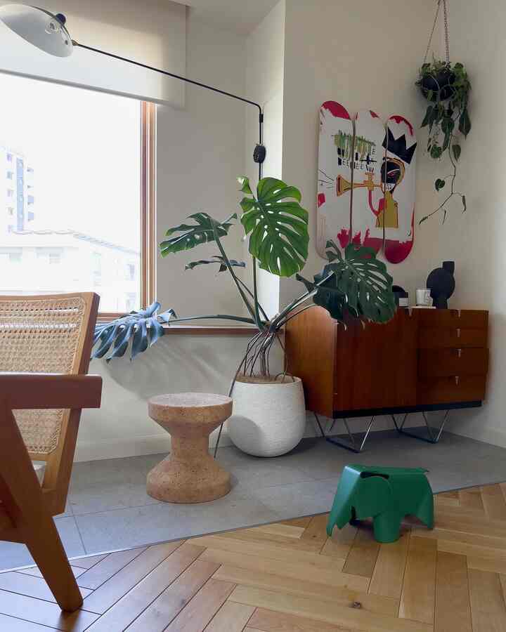 Natural-tone living room featuring cork stool, large monstera plant, and Vitra Eames Elephant Small toy