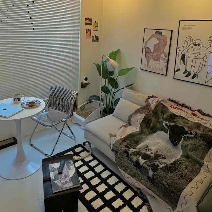 Natural-tone white living room featuring a white sofa, patterned carpet, and small round coffee table with cozy ambiance