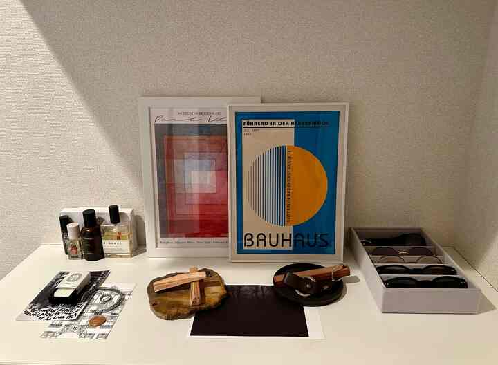 Simple entrance space with white walls and countertop featuring Bauhaus posters and various objets neatly arranged
