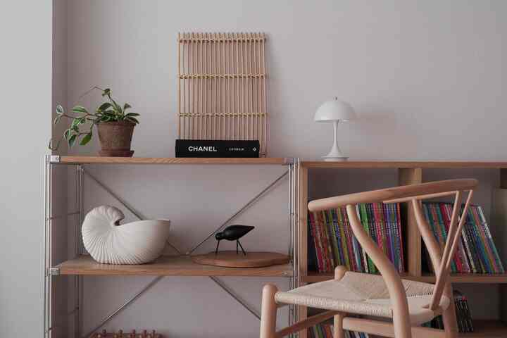 ナチュラルな木目調の子供部屋、木製の椅子とカラフルな本棚、シンプルなテーブルランプが配置された落ち着いたインテリア