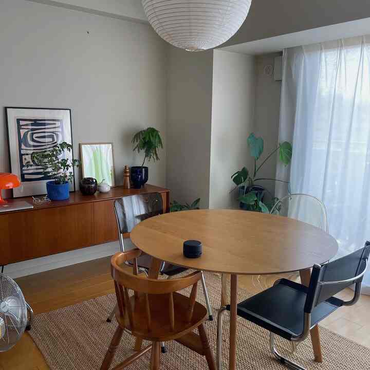 ウッドトーンとベージュの色調のダイニング、丸いダイニングテーブルと様々な椅子、サイドボードや植物が印象的な雰囲気をつくるインテリア。