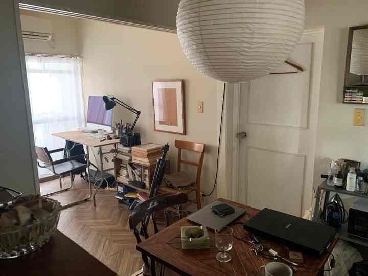 白い壁と木目調家具が配置されたワンルームのホームオフィス、シンプルで北欧風の落ち着いた雰囲気のインテリア