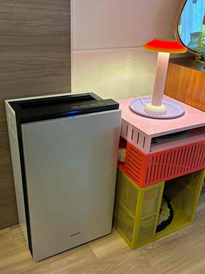 シルバーと赤、黄色の色調のリビングの一角にステンレスの空気清浄機とカラフルな収納ユニット、ランプが配置されたモダンな空間