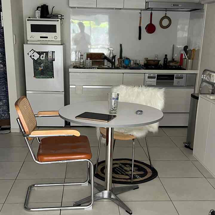Bright white-toned kitchen space featuring a round dining table and mid-century modern chairs, creating a cozy atmosphere