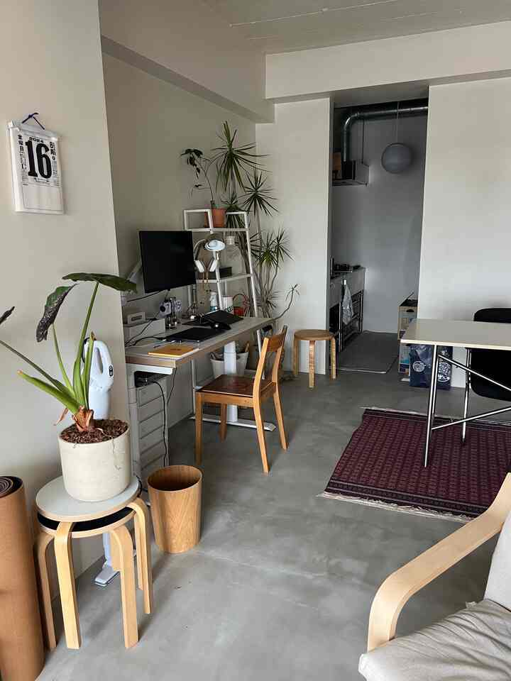 Natural-toned compact workspace featuring desk, stools, and plants in a neat home office