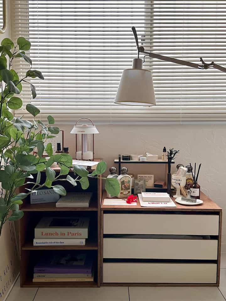 Natural tone bedroom featuring wooden cabinets, vanity, table lamp, and plants creating a cozy atmosphere