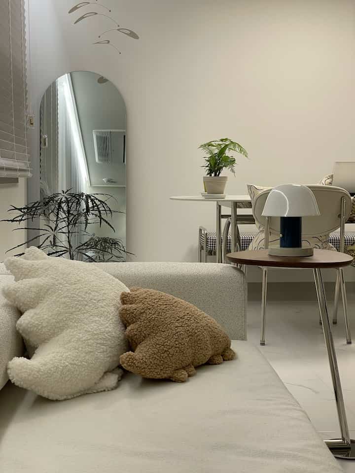 アイボリーとブラウンの色調のリビングとダイニング、ソファや植物、テーブルランプが配置された雰囲気あるインテリア