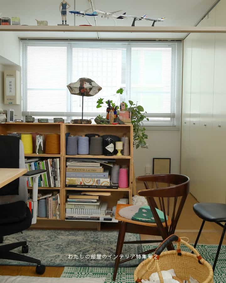 A white and wood-tone single household workspace featuring bookshelves and armchair with cozy interior