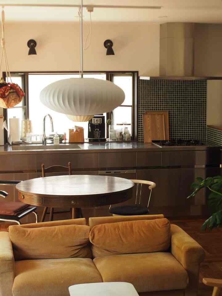 温かみのあるブラウン調のリビング・キッチンスペース、ライトブラウンのコーデュロイソファと丸テーブルが配置されたナチュラルモダンなインテリア