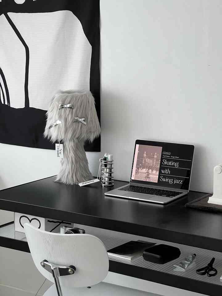 黒と白のミニマルなホームオフィス、黒いデスクにグレーのテーブルランプとMacBookが置かれた清潔感のある空間