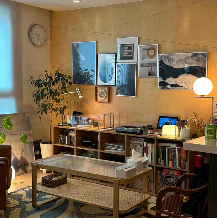 ナチュラルな木目調の壁にソファ、LPターンテーブル、植物が置かれた居心地の良いリビングルーム