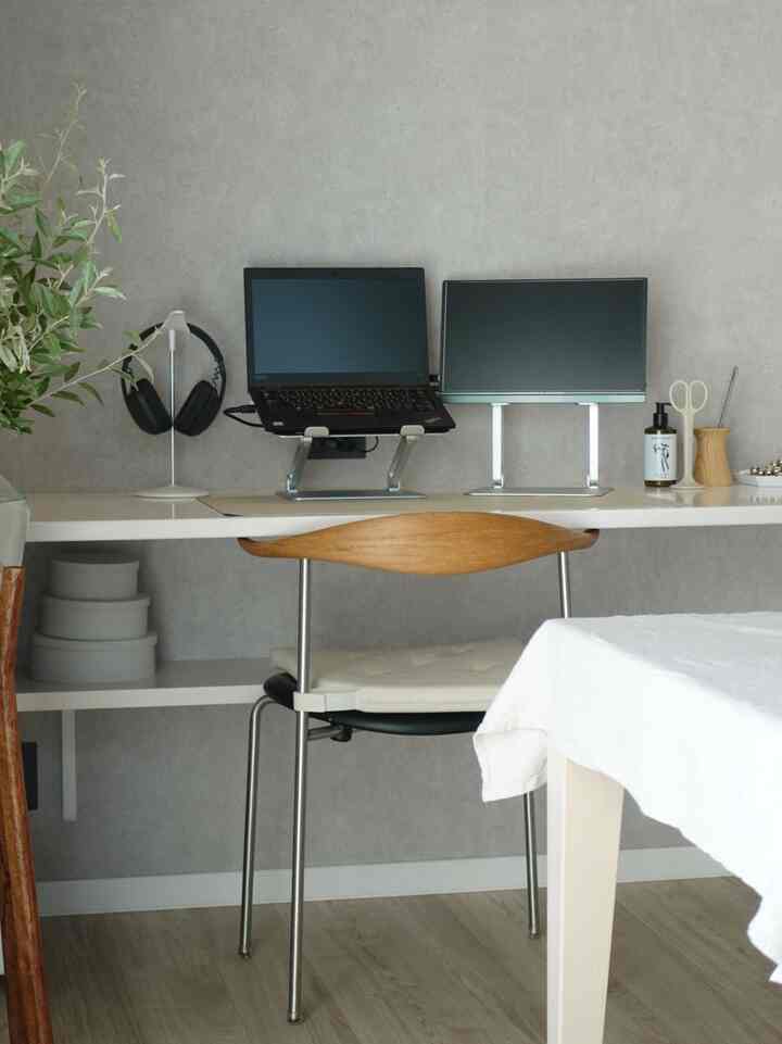 Gray wall backdrop with white desk and wood-tone chair in a simple modern home office workspace