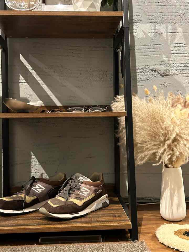 Gray wall with wood tone shelving in a single household living room, featuring a white vase with dried flowers in a modern, natural setting
