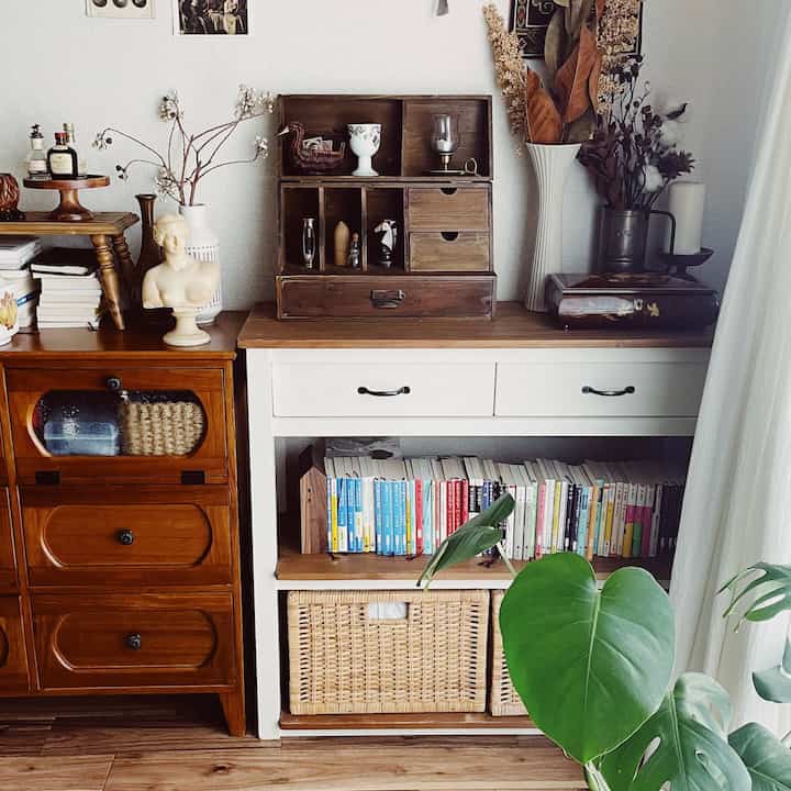 ナチュラルカラーのヴィンテージリビング、白いコンソールテーブルと木製キャビネット、植物が配された雰囲気のあるインテリア