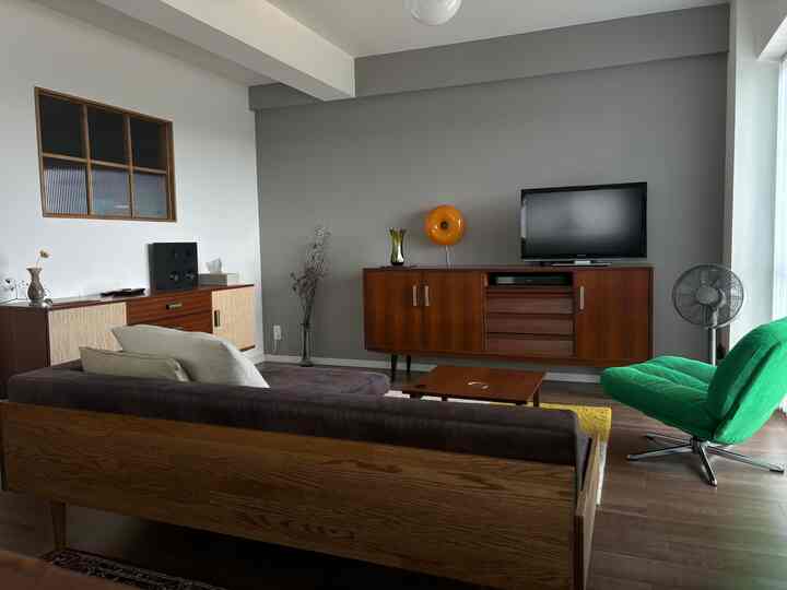 Mid-century modern living room with wood tones and gray walls, featuring wooden furniture and a green armchair near window