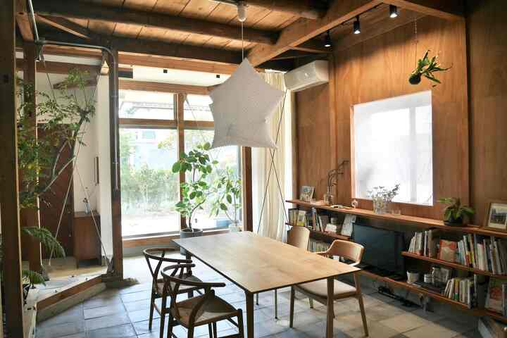 Natural tone living room featuring a 4-person oak dining table, plants, and a white pendant light creating a cozy atmosphere