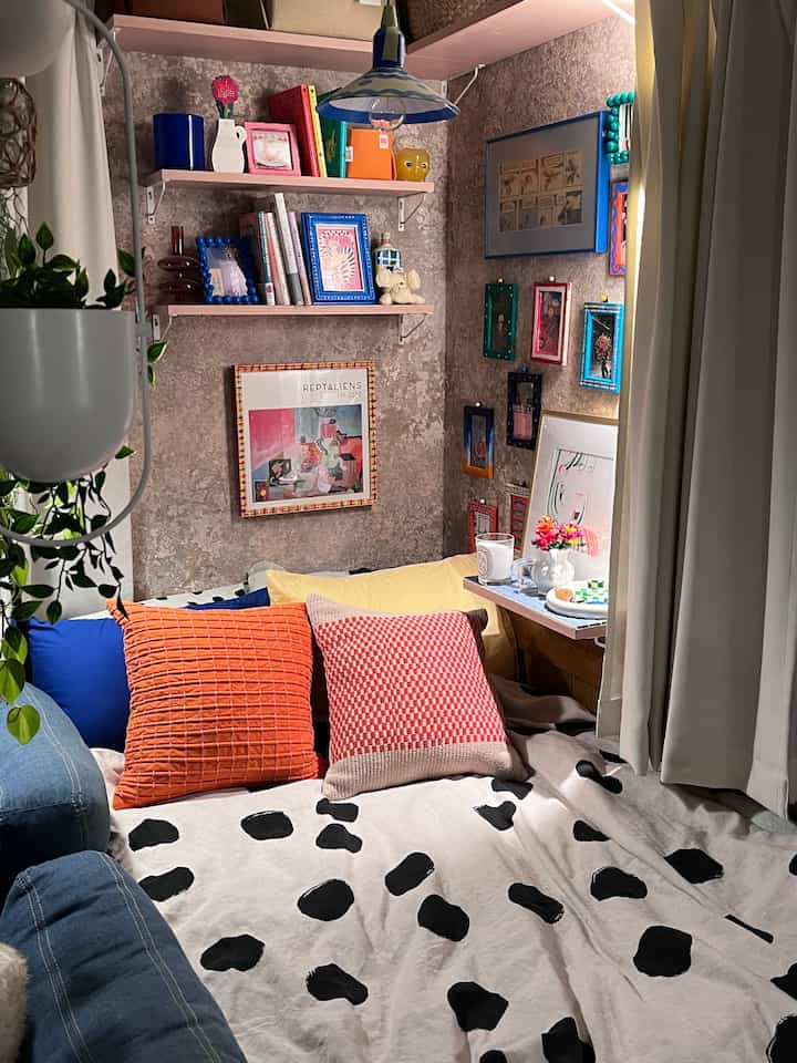 Blue and orange toned bedroom featuring assorted cushions and framed art creating a cozy atmosphere