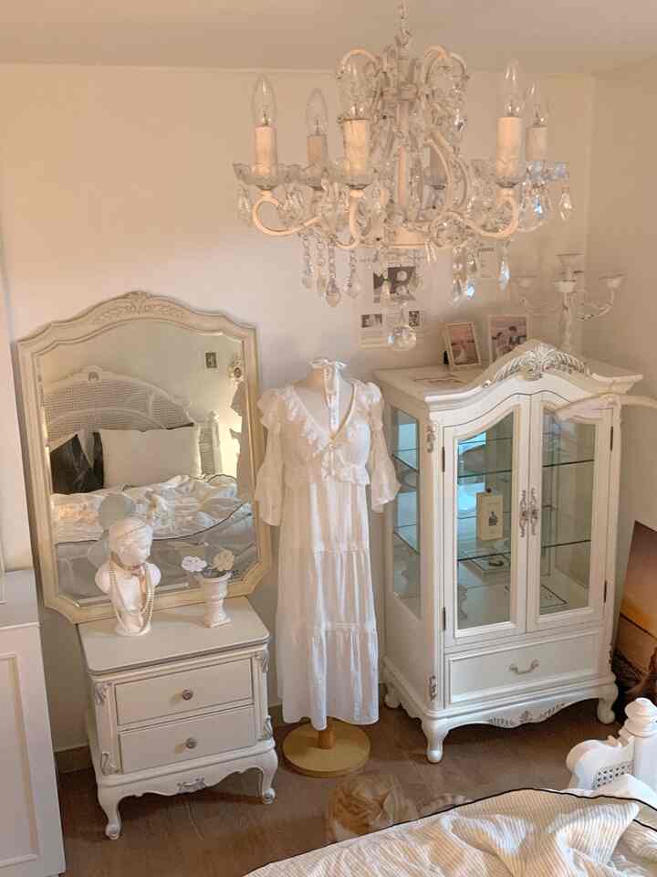 白を基調とした寝室、アンティーク家具とクリスタルシャンデリアが配置されたクラシックで上品なインテリア