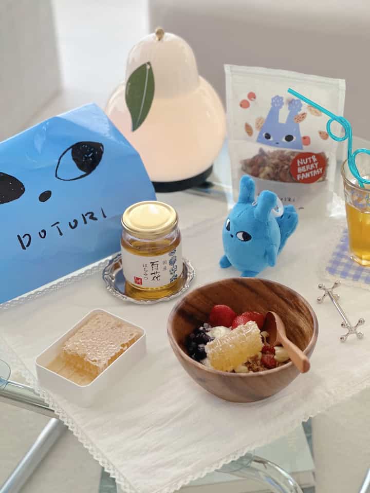 Natural-toned table featuring an acacia wood bowl with fruit, honeycomb, and cozy home cafe setup