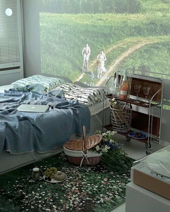 白と緑の色調の寝室、フラワーガーデン柄のラグとベッド、ラタンバスケット、バーカートが配置された自然で落ち着いたインテリア