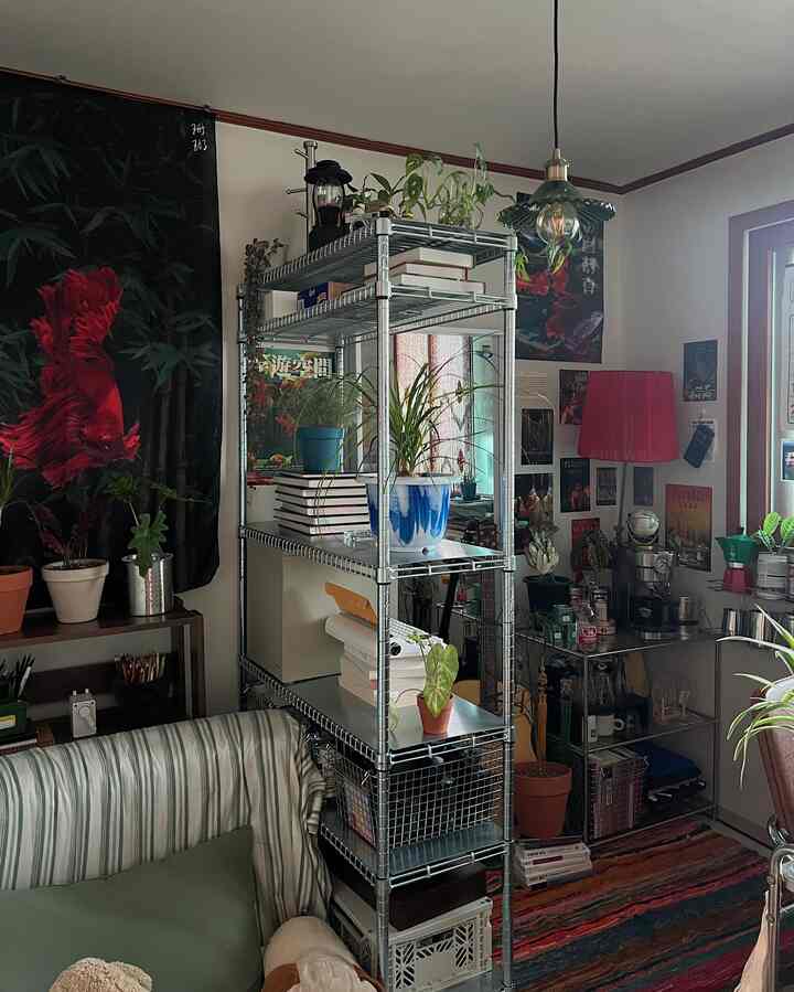 中央に鉄製棚と多様な植物、壁の装飾が配置されたレトロ調の小さなホームオフィス空間