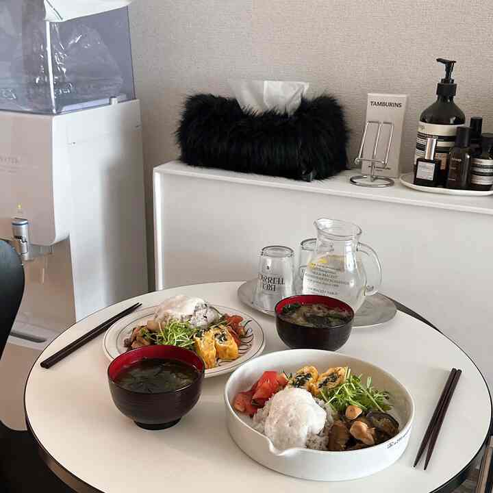 白を基調としたダイニング、丸テーブルに食事が置かれたシンプルで清潔感のある雰囲気のインテリア