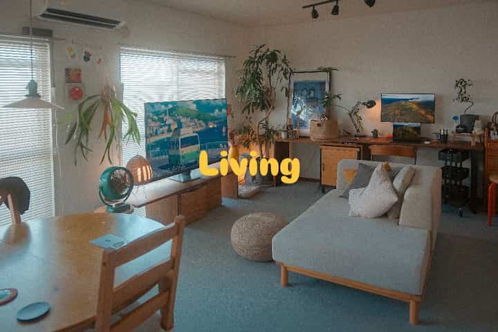 ナチュラルな色調のリビングとダイニング、ソファとダイニングテーブル、植物が配置された落ち着いた印象の空間