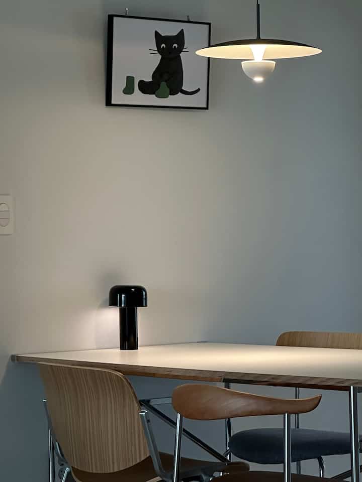 白い壁とテーブル、ナチュラルウッドのダイニングチェアが配置されたモダンで清潔感のあるダイニング空間