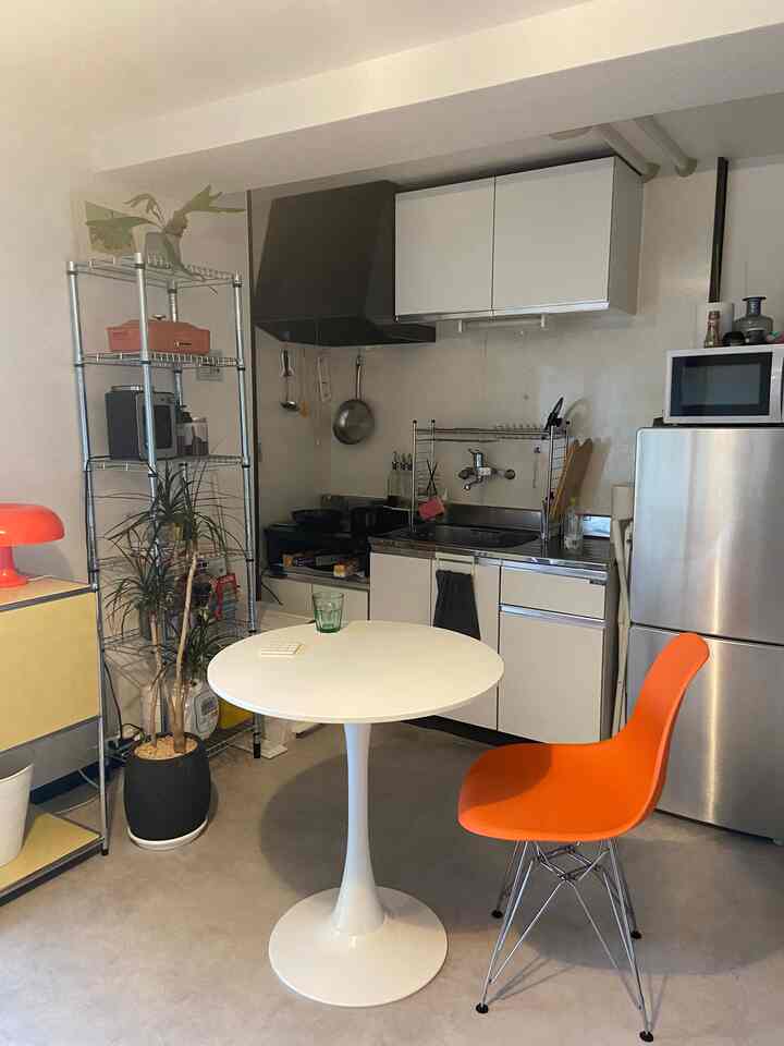White and orange toned 1DK kitchen and dining space featuring a round dining table and mid-century modern chair creating a cozy atmosphere