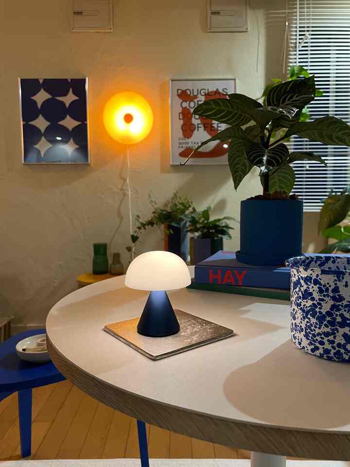 ブルーとオレンジの色調が特徴の北欧ミッドセンチュリーモダンなリビング、テーブル上にLEDのキノコ型ランプと植物が配された雰囲気のある空間