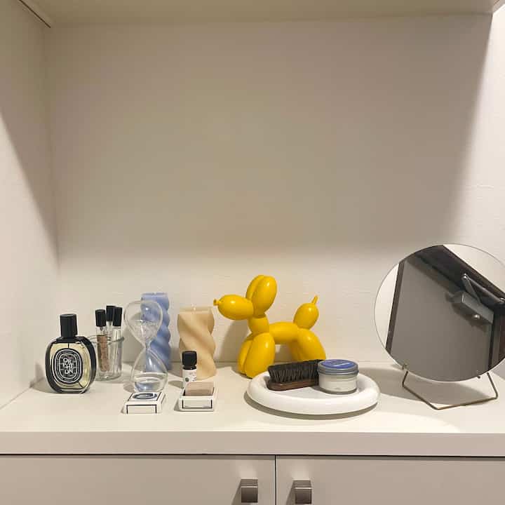 白を基調とした玄関スペース、ライトブルーとクリーム色のツイストキャンドルと黄色いバルーン犬のオブジェが配されたモダンなインテリア