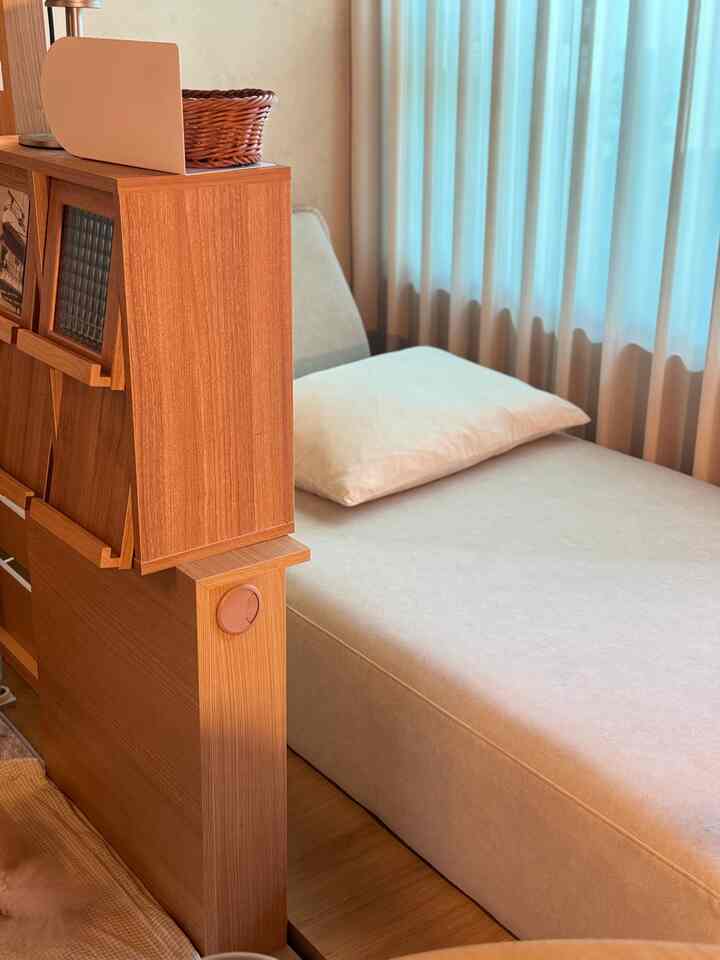 ナチュラルな木目調とベージュのソファベッドが配置された雰囲気のある間仕切りされたワークスペース