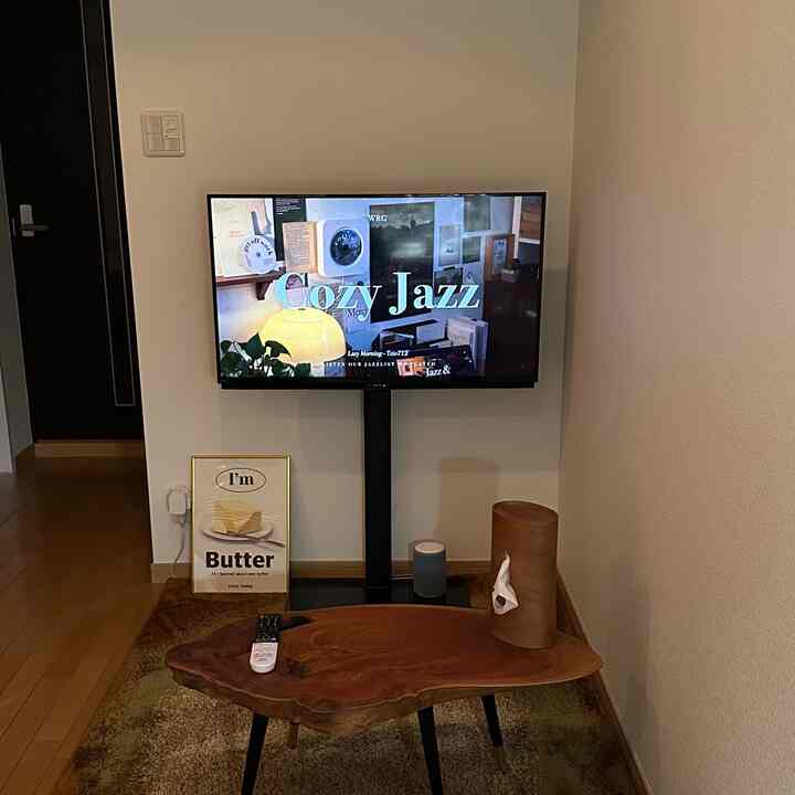 Wood tone, simple studio living room featuring a TV stand and natural wooden table in a clean space