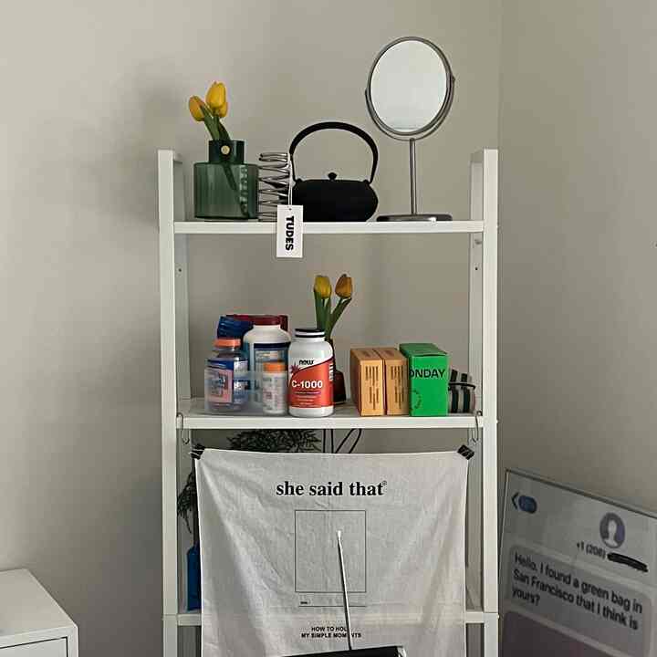 White tone kitchen space featuring IKEA metal shelf with yellow tulips and multi-use objects neatly arranged for single household storage ideas