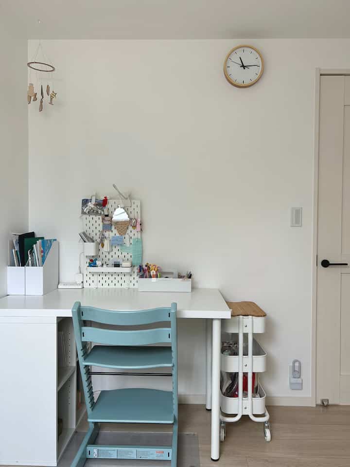 A simple kids' room with white and wood tones, featuring a clean desk and a light blue chair