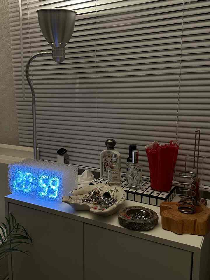 ホワイトとシルバーのトーンが特徴のモダンな狭い部屋、EKETチェスト、フロアランプ、LED時計が配置されたインテリア