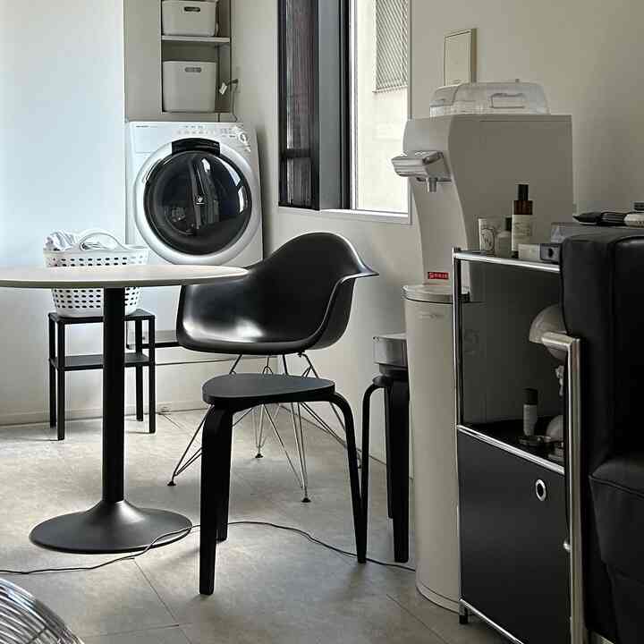 Modern studio apartment in white and black tones featuring a round table and washing machine in a functional layout