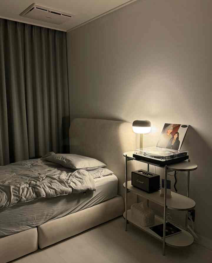 柔らかいベージュ色調の寝室、ベッドとターンテーブルが配置されたモダンな一人暮らしのインテリア