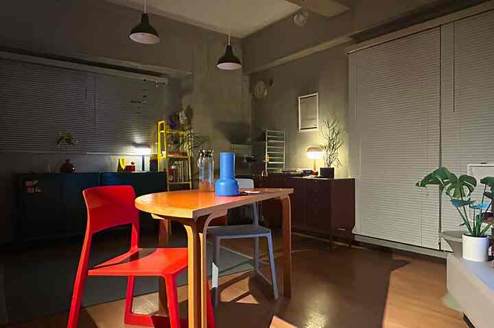 Wood tone dining room with red chair, warm lighting and blue decor on table creating cozy atmosphere