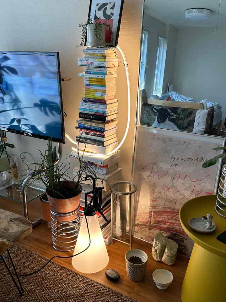 ホワイトとナチュラルトーンのリビング、印象的な本棚とフロアランプがある雰囲気のあるインテリア