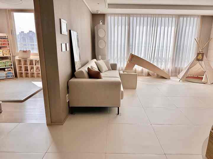 ベージュ色調のリビング・子供部屋空間、ソファと子供用遊具が配置された自然で明るい印象的なインテリア