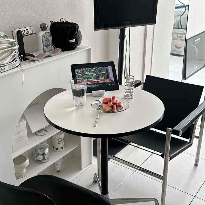 White and black toned living room featuring a round dining table, chairs, and TV with a simple modern atmosphere