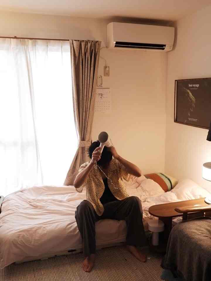 ベージュの壁とカーテンがある居心地の良い寝室、中央にベッドが配置され、温かみのある雰囲気のインテリア