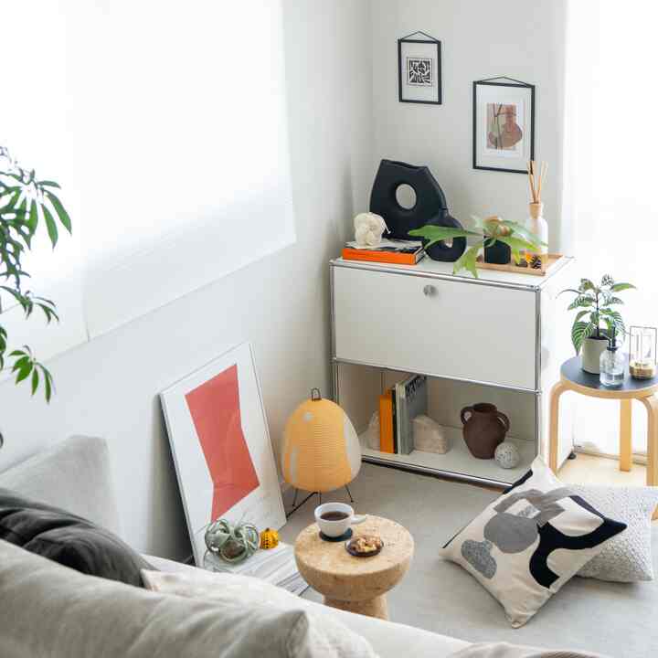 ホワイトトーンのリビング、シンプルなサイドボードと植物が配置された落ち着いた雰囲気のインテリア